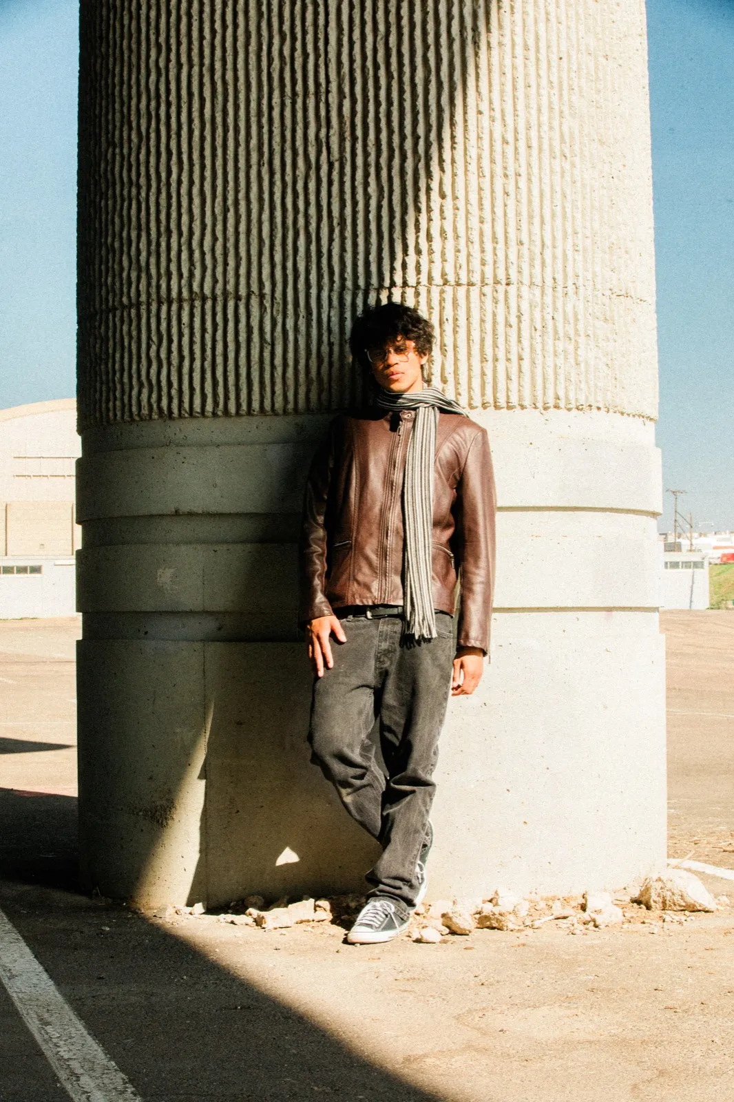 phaseeluv leaning on a concrete pillar in golden-hour light